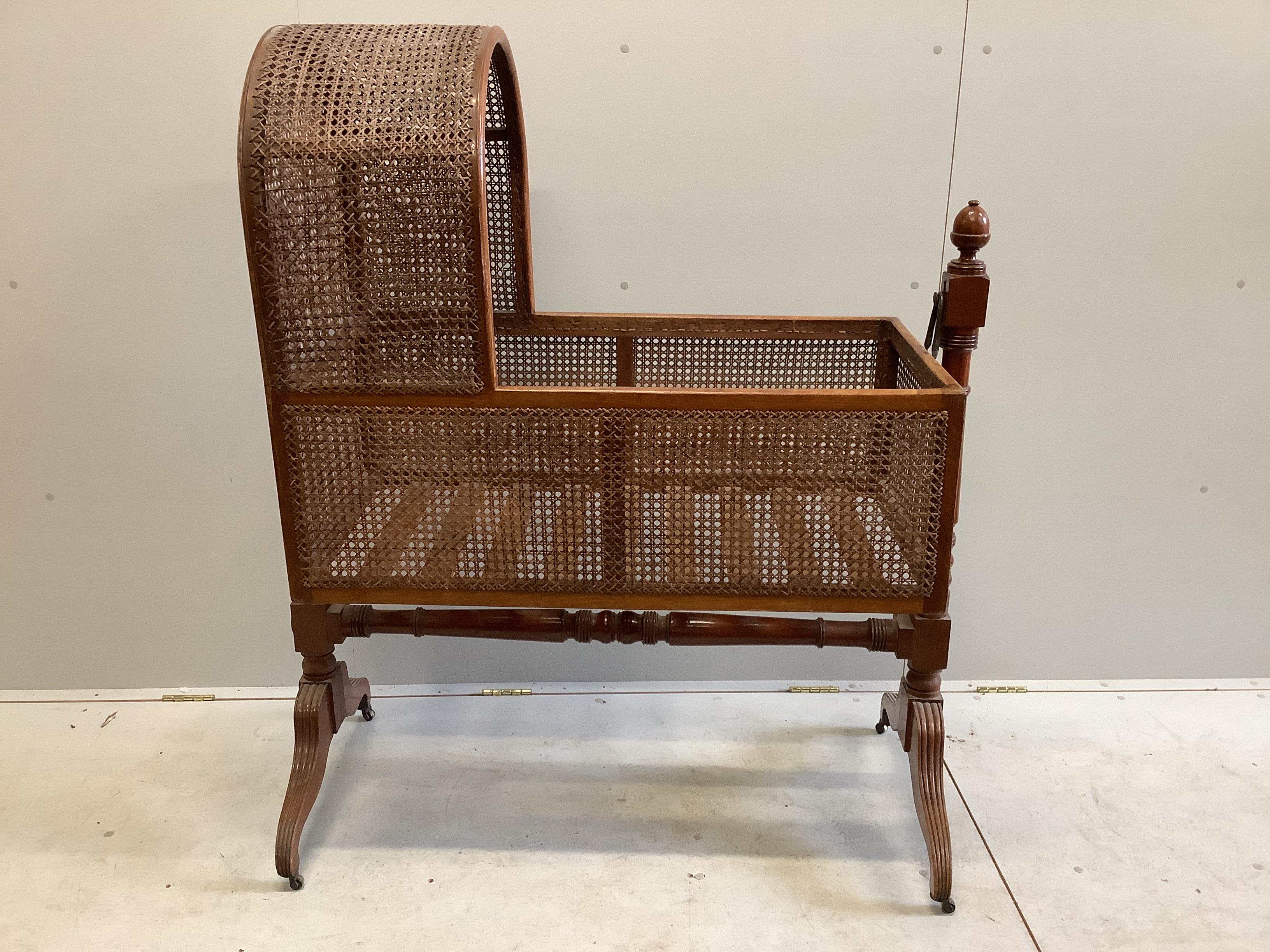 A George IV caned mahogany rocking crib, width 112cm, depth 51cm, height 135cm